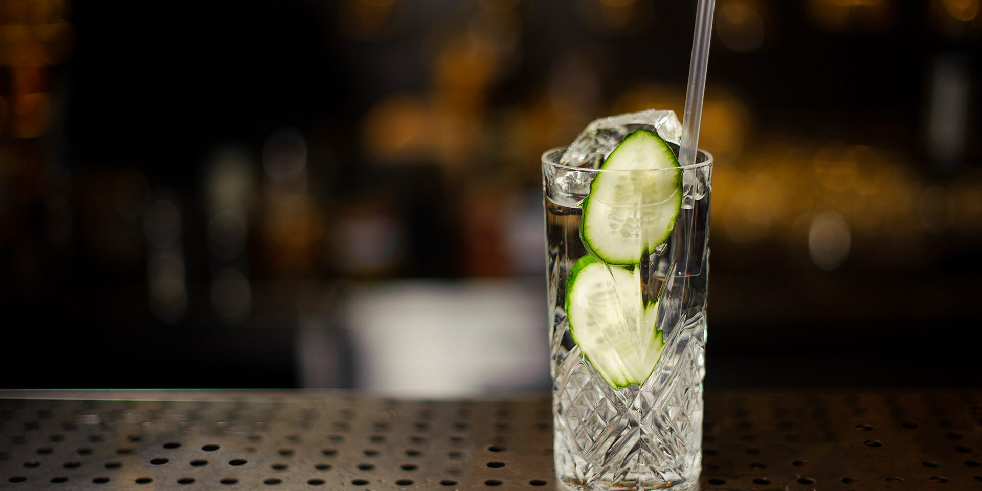 Cocktail glass filled with fresh alcoholic drink with cucumber slices and gin Cocktail glass filled with fresh and tasty alcoholic drink with cucumber slices and gin on the bar counter