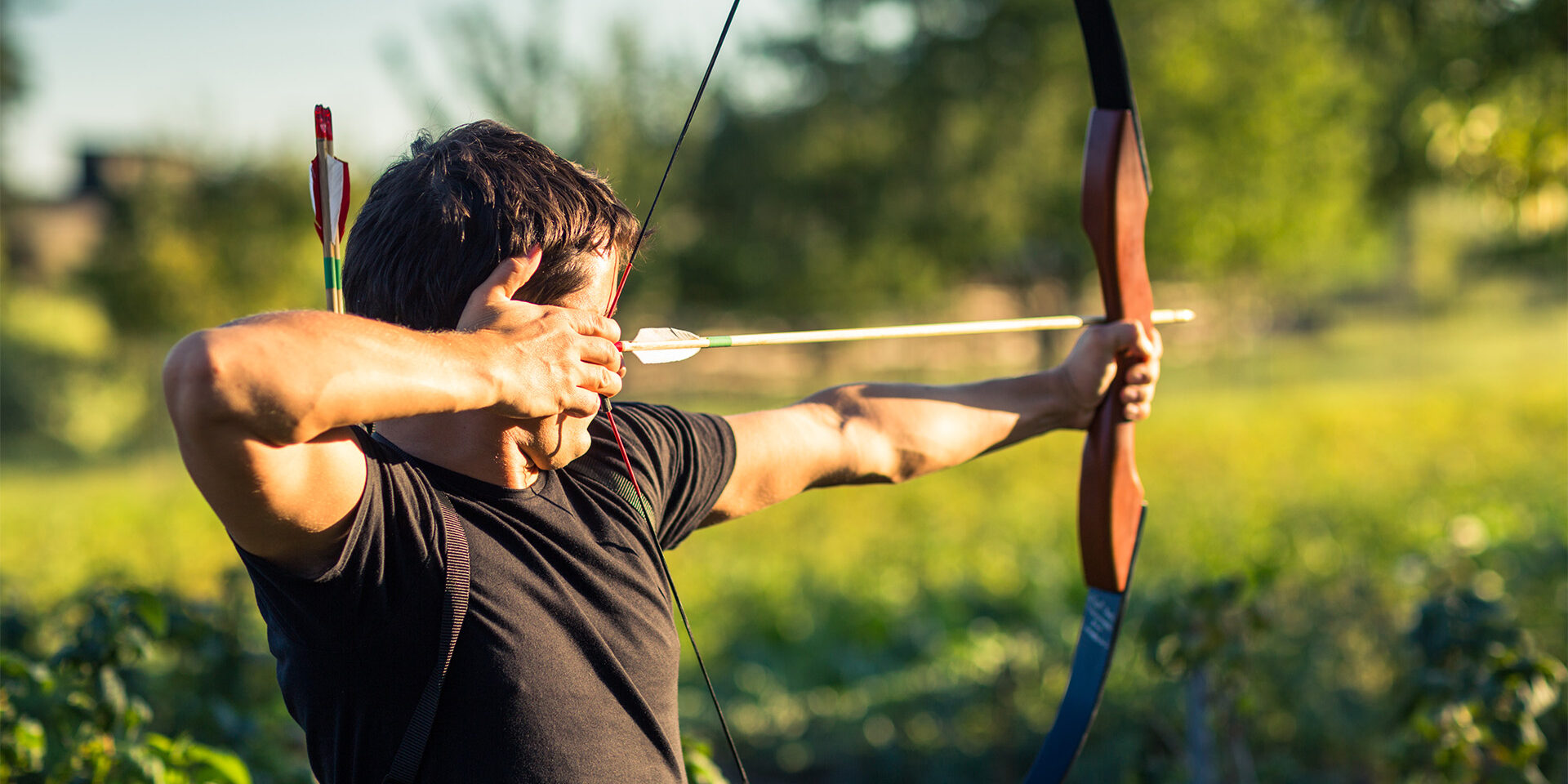 Young archer training with the bow in a city park