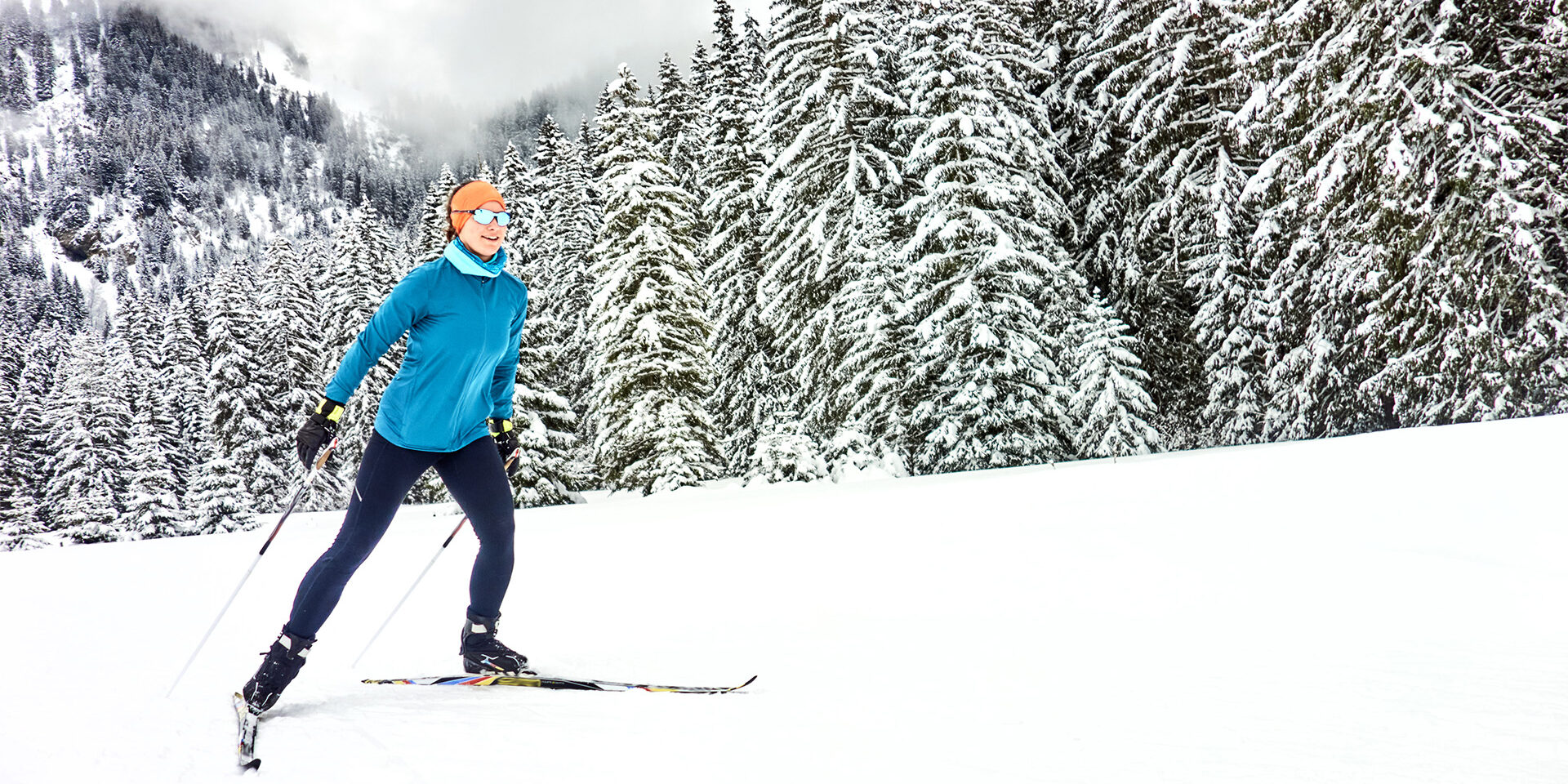 Female skate skier follows track towards forest In the snowy Swiss Alps, in winter