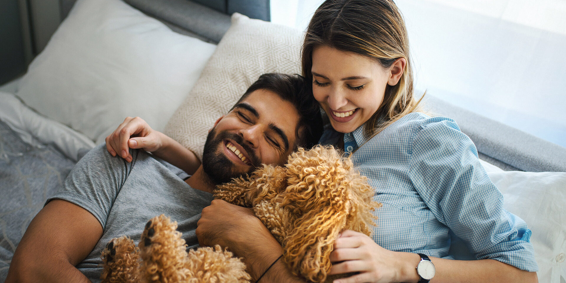 Closeup side view of a happy young couple at home having fun with their pet dog.