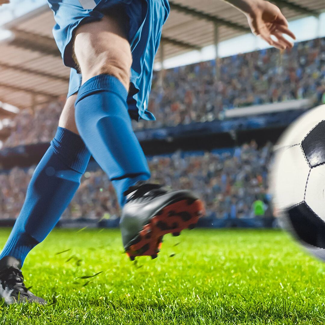 Football World Championship: Soccer Player Runs, Kicks the Ball. Ball Shoots, Grass Sprays Outwards, Full Stadium Crowd Cheers. Cinematic Shot Captures Glorious Victory. International Tournament.