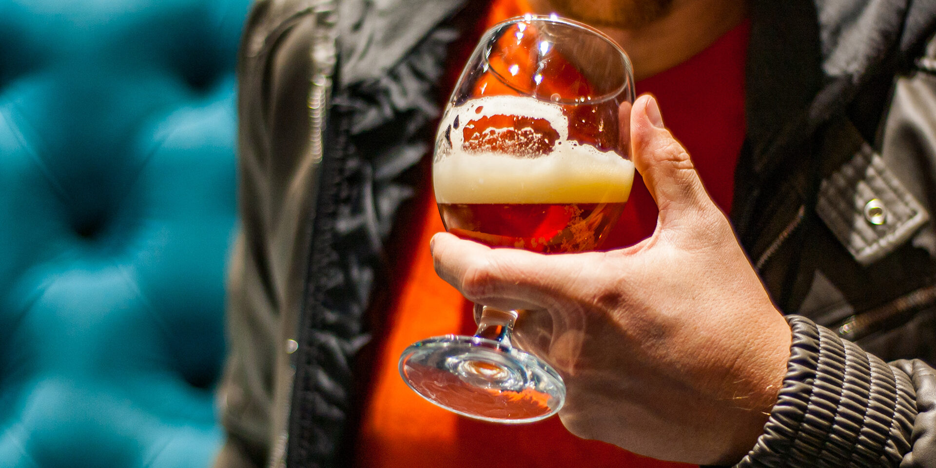 man's hand holds a glass of amber Pale Ale beer in bar man's hand holds a glass of amber Pale Ale beer in bar