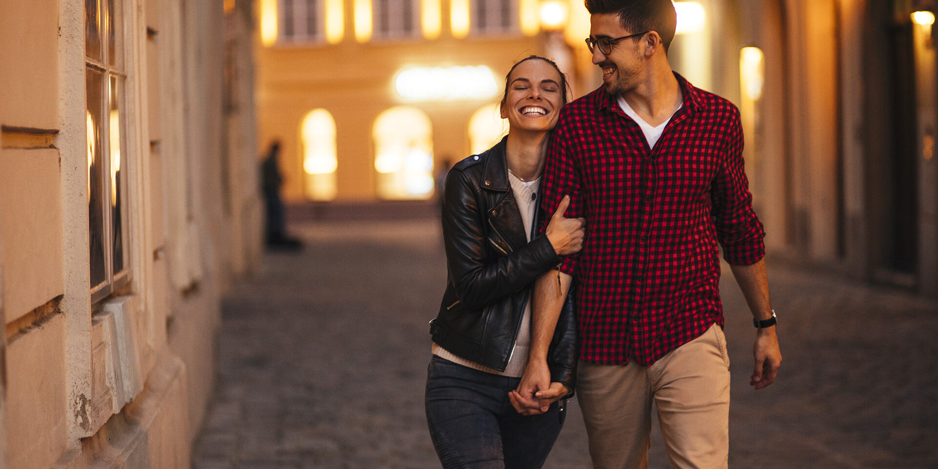 Happy young couple walking in a beautiful city in the evening