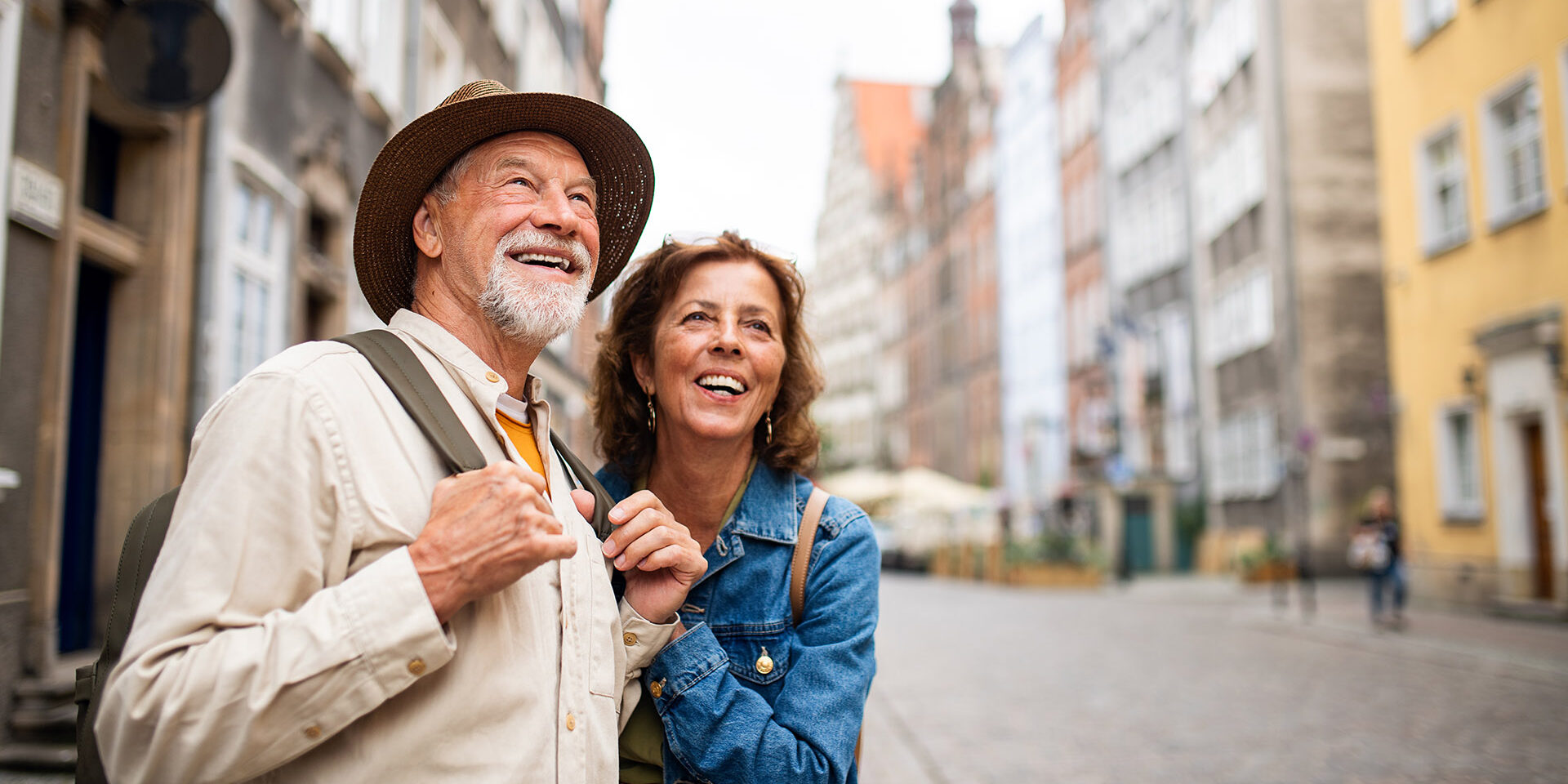 A portrait of happy senior couple tourists outdoors in historic town