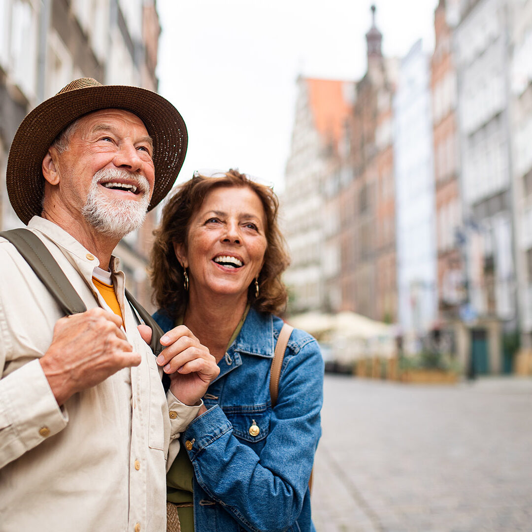 A portrait of happy senior couple tourists outdoors in historic town