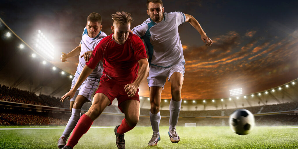 Soccer players in action on the sunset stadium background panorama