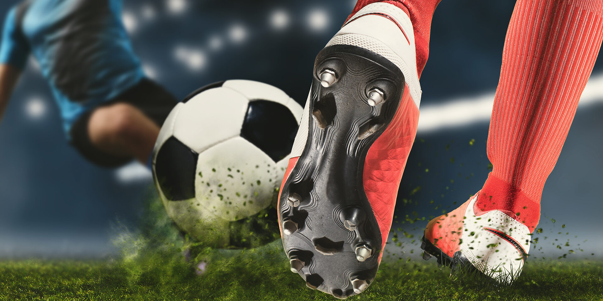 Football player man in action on dark arena background. Soccer player making sliding tackle