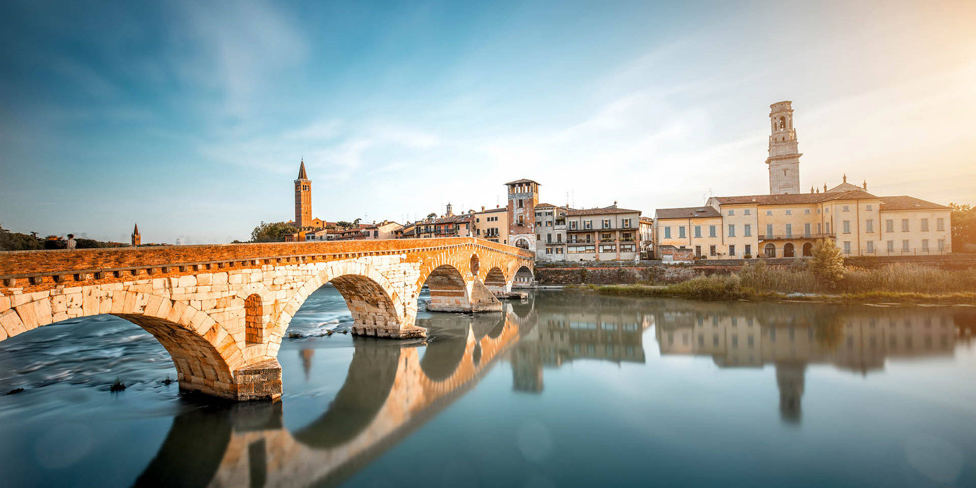 Verona cityscape view on the riverside with historical buildings and towers on the sunset