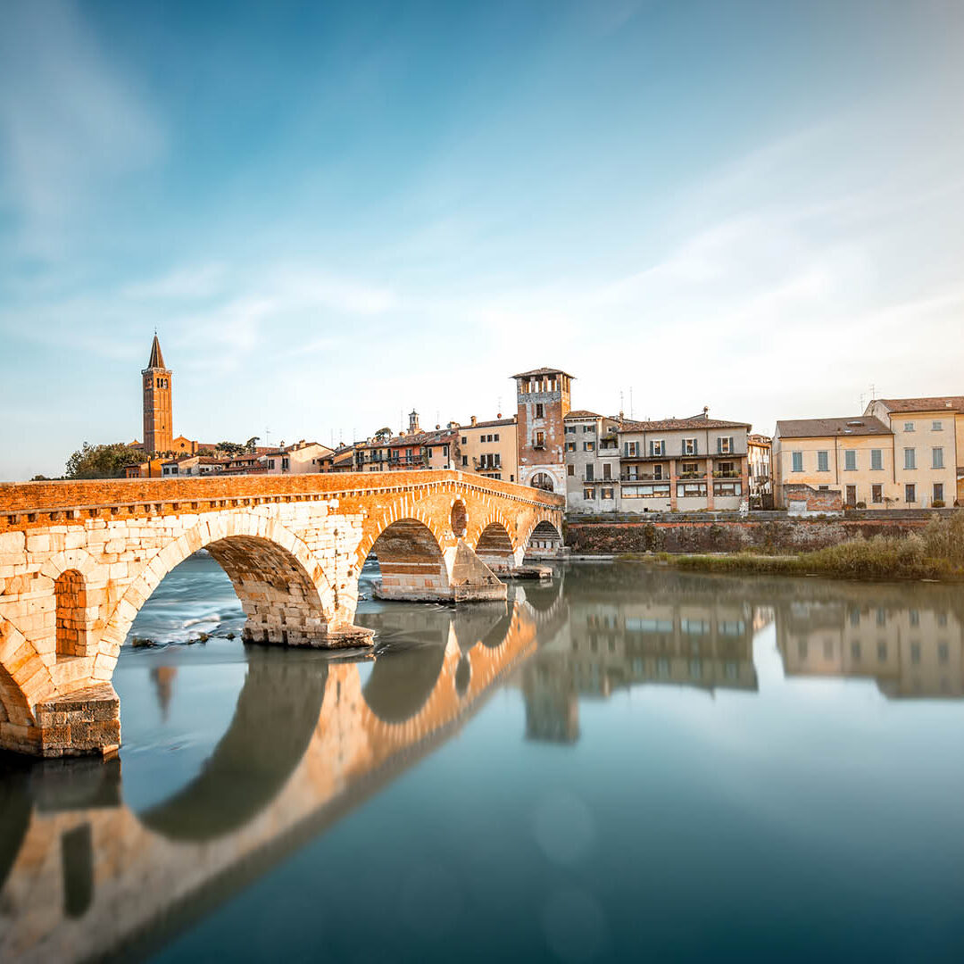 Verona cityscape view on the riverside with historical buildings and towers on the sunset