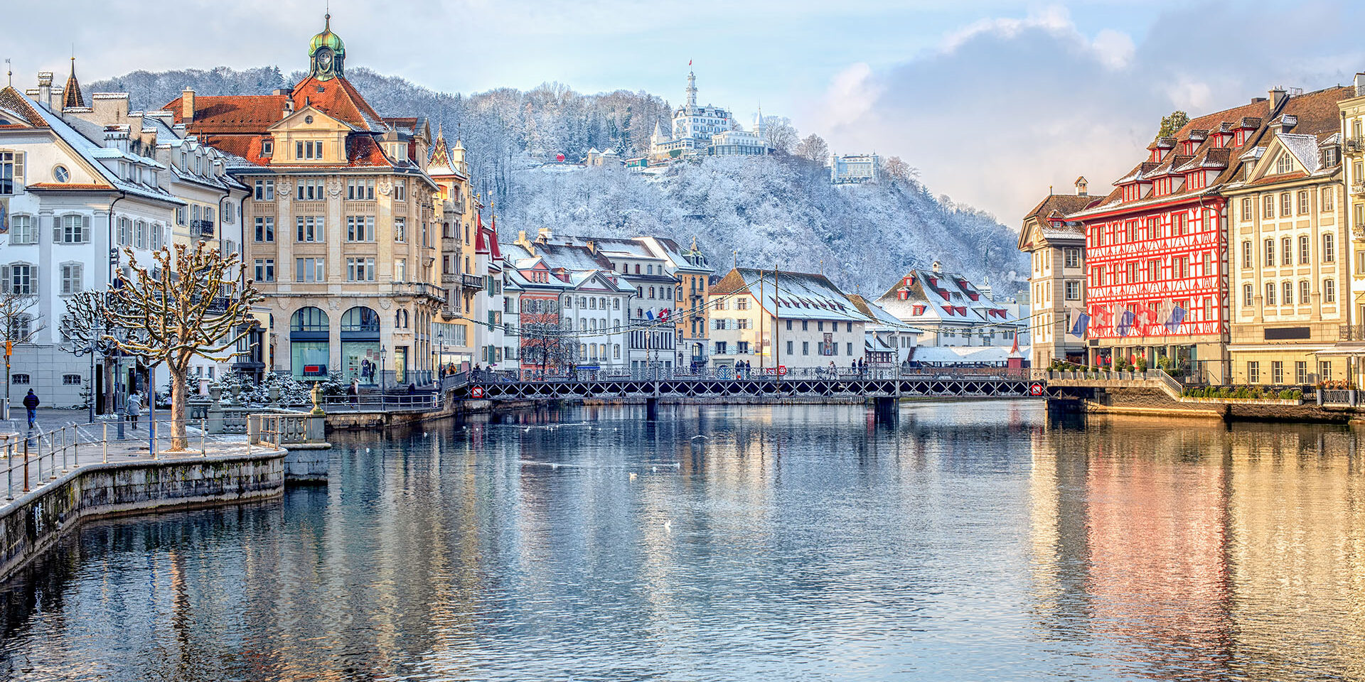 Lucerne city, Switzerland, view of the Old Town covered with white snow in winter, reflecting in the river