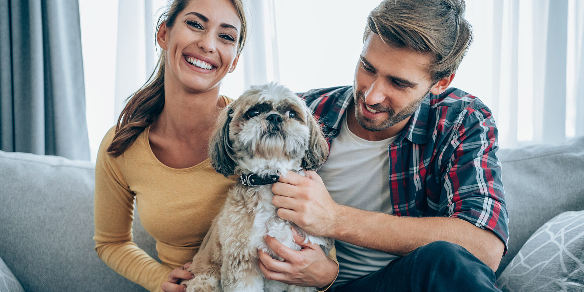 Shot of an affectionate young couple relaxing with their pet dog on the sofa at home.