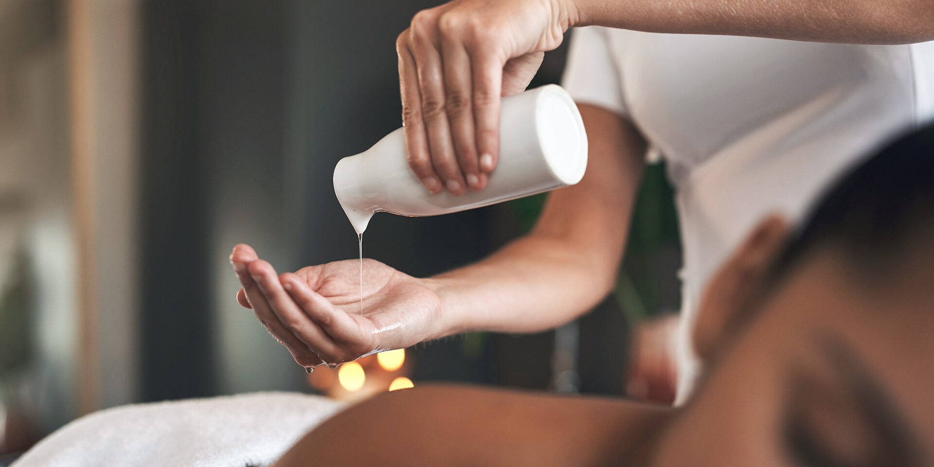 Closeup shot of a massage therapist pouring body oil into her hands while giving a massage to a customer at a spa This soothing massage oil will work wonders