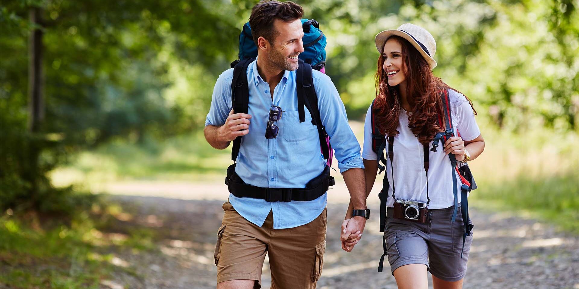 Happy couple hiking together in mountains with backpacks