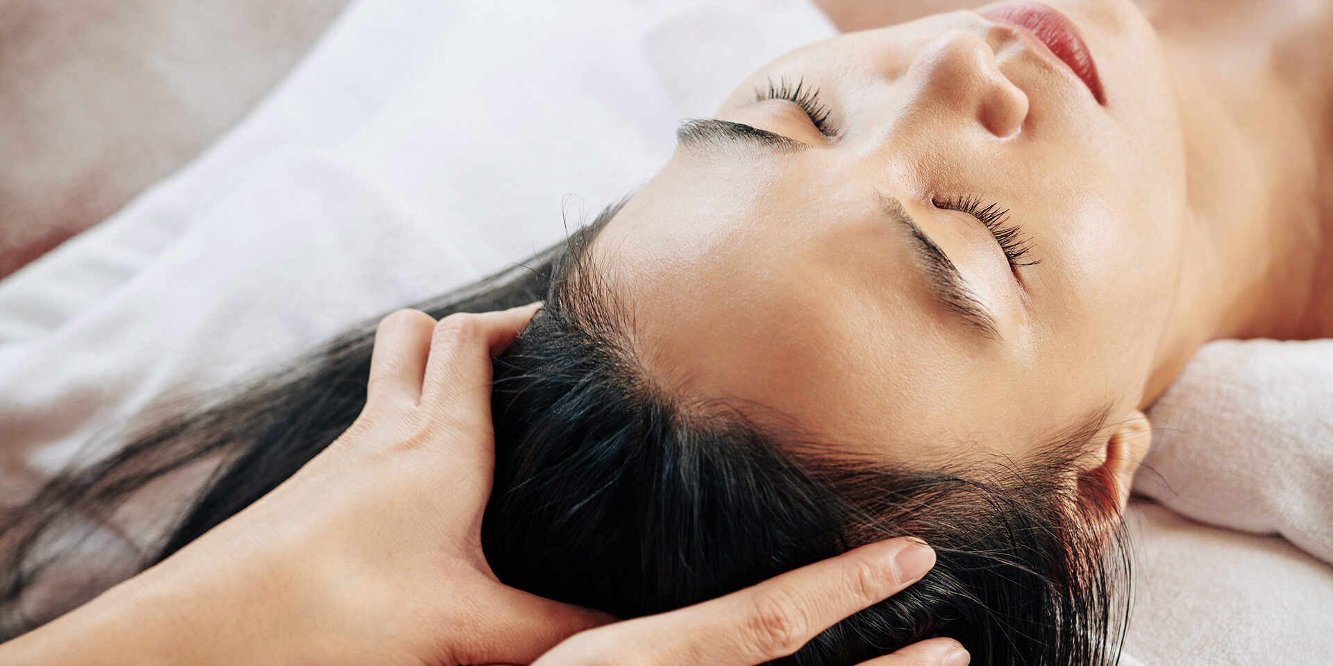 Professional head massage Close-up image of beautician massaging head of female client relaxing on massage bed