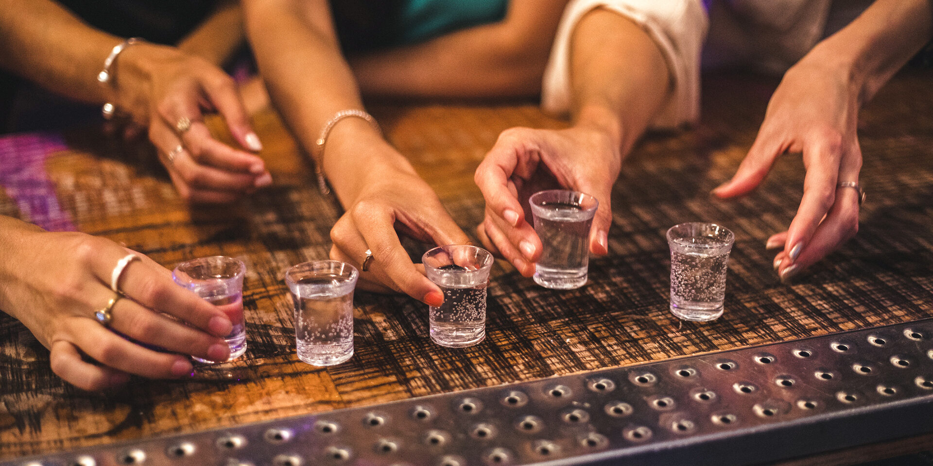 Women about to pick up some shot glasses for their night out.