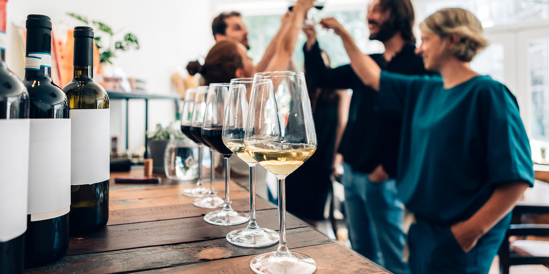 people inside a bar chilling out with a drink - friends talking and drinking in a winery - Millennials toasting at a wine tasting